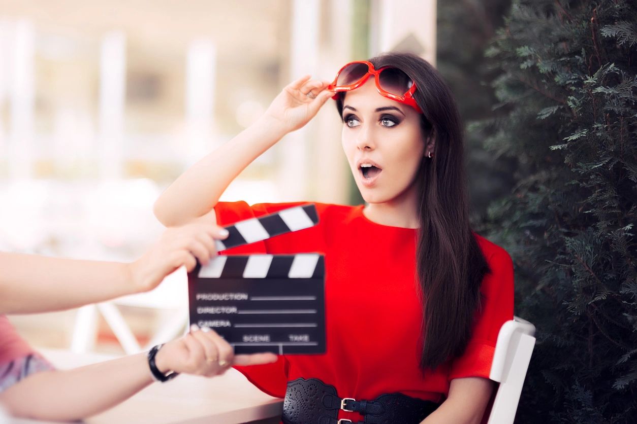 A woman holding a movie clapper board up to her head.