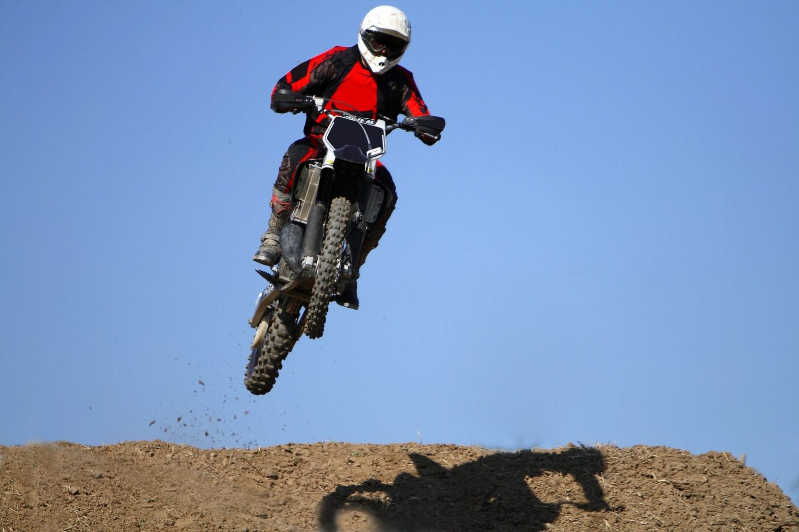 A person on a motorcycle jumping over some dirt