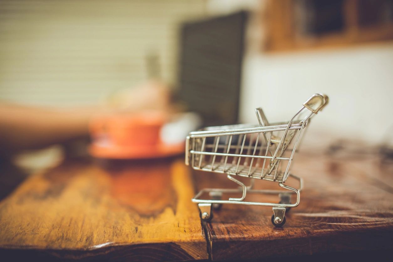 A small shopping cart sitting on top of a wooden table.